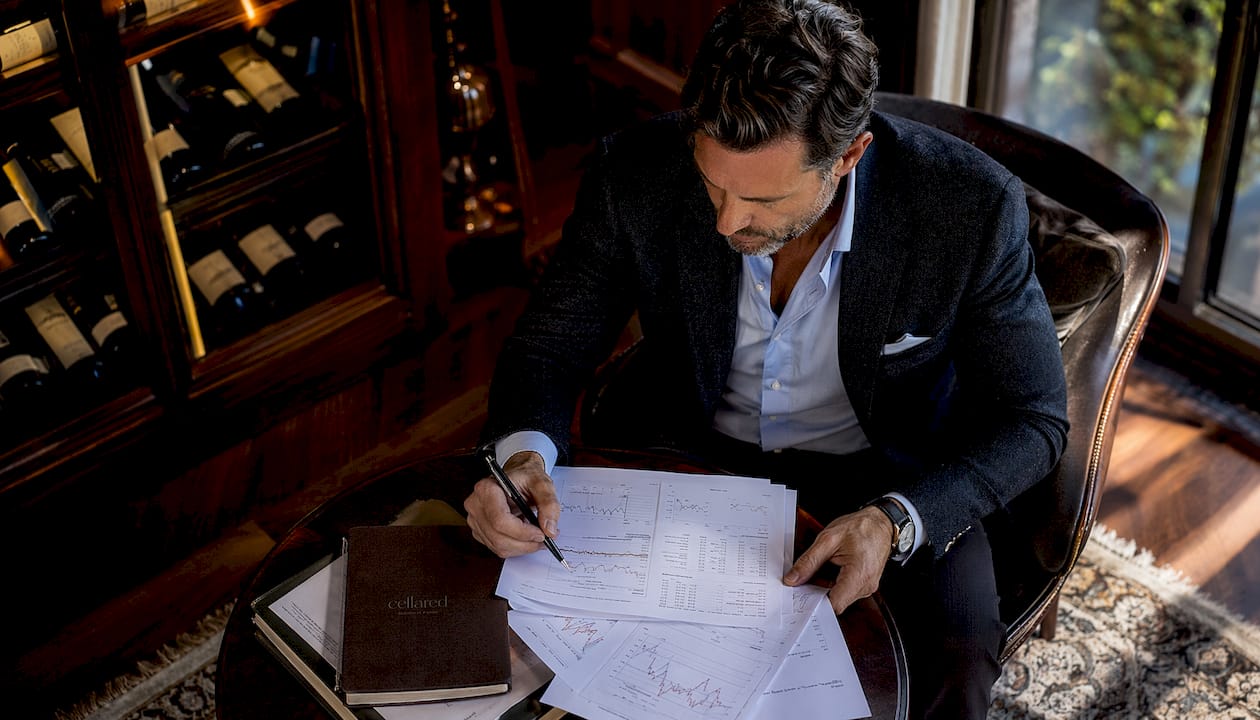 Man analyzing vintage wine price charts at desk