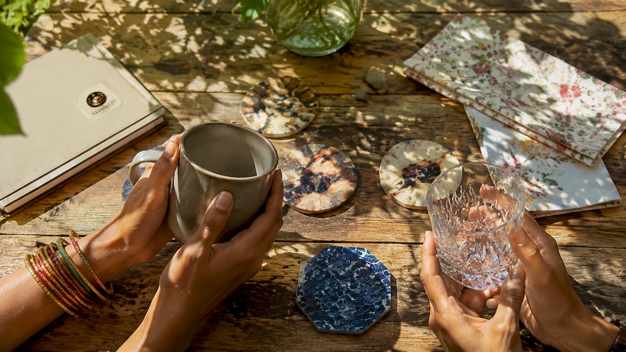 Hands comparing stainless steel and crystal glasses overhead