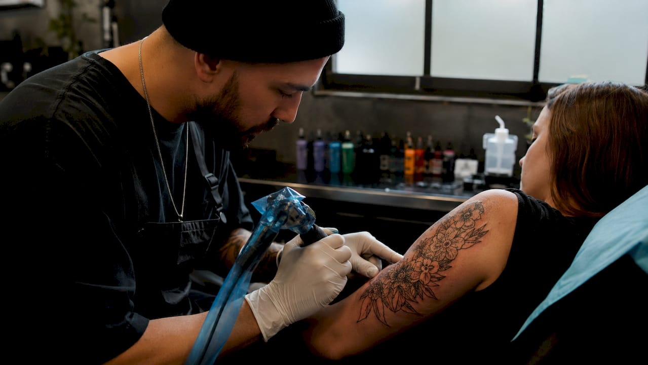 Close-up of tattoo artist’s hands tattooing arm