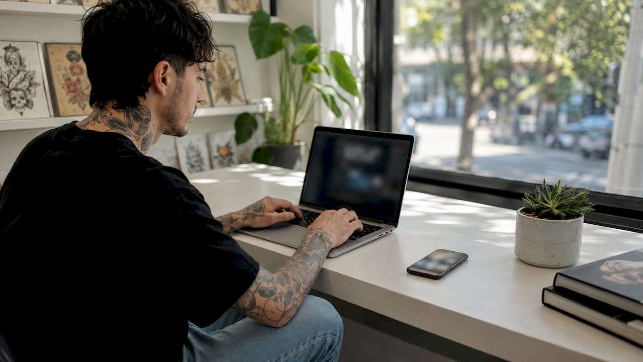 Hands typing on laptop managing tattoo appointment reminders
