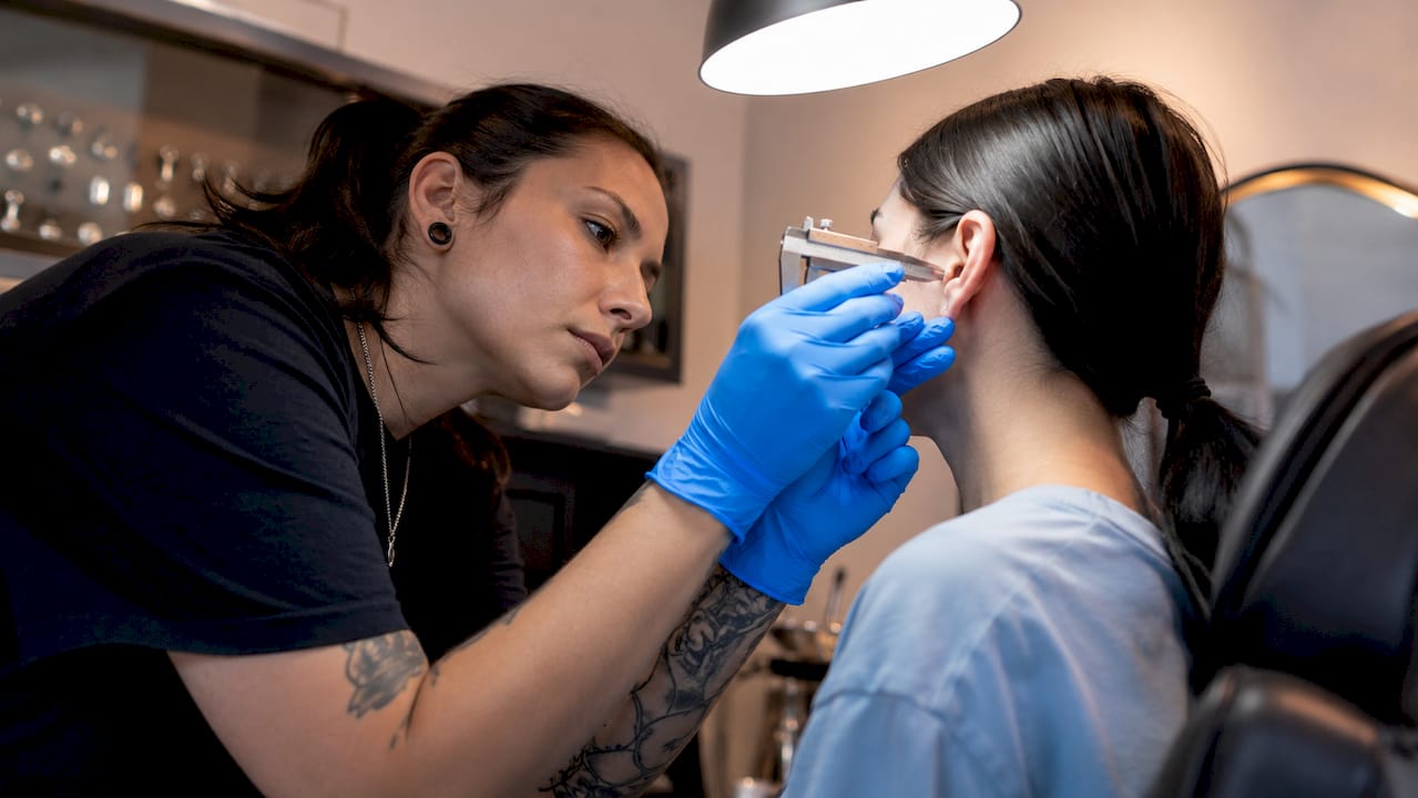 Piercer examining client ear anatomy