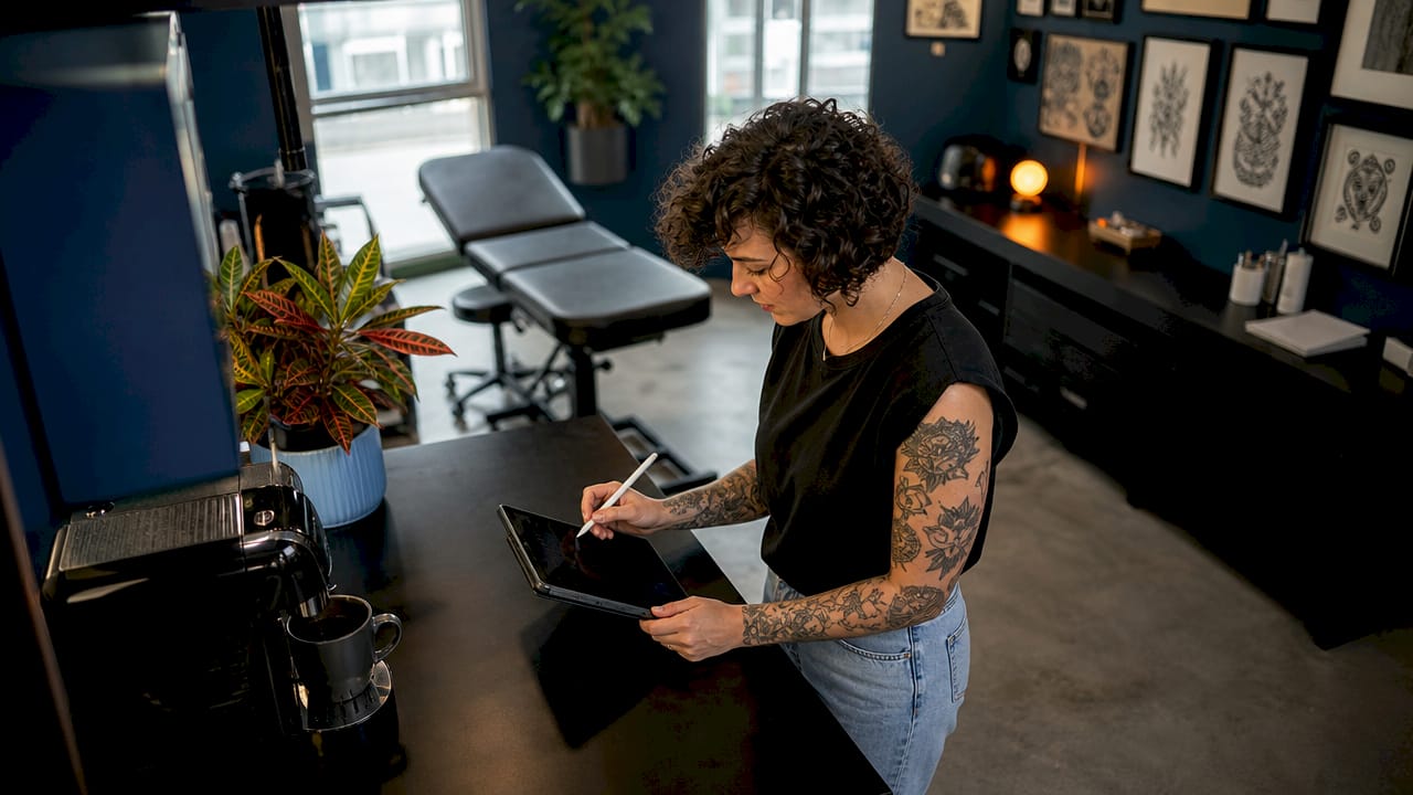 Tattoo studio owner managing bookings at desk