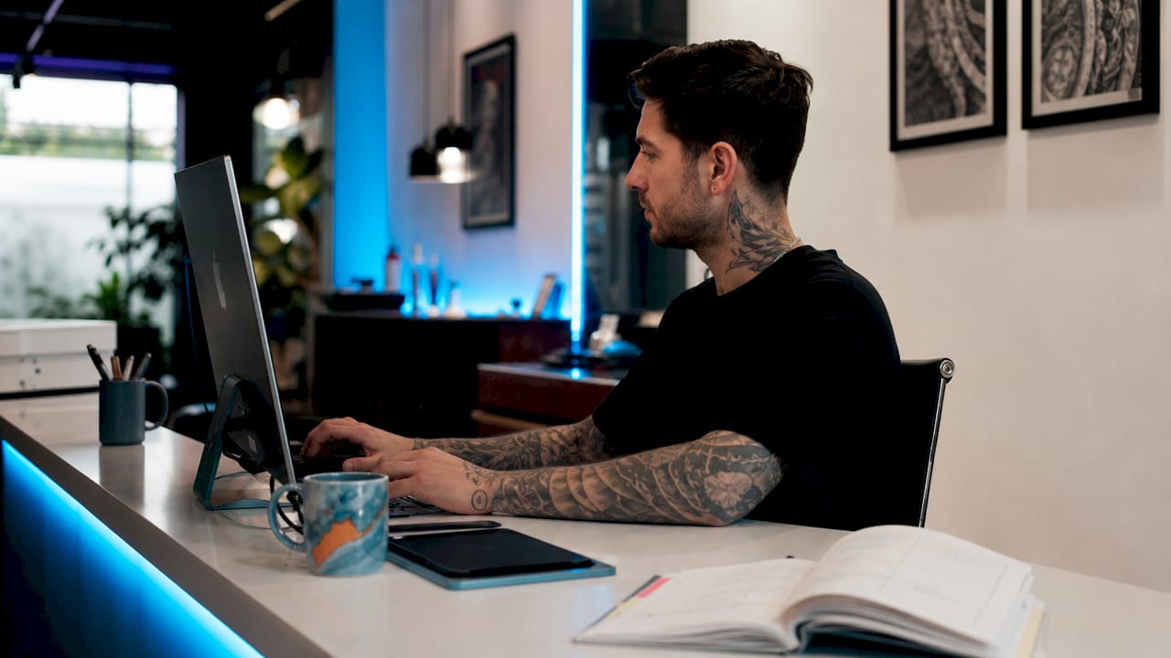 Tattoo artist booking appointment at studio desk