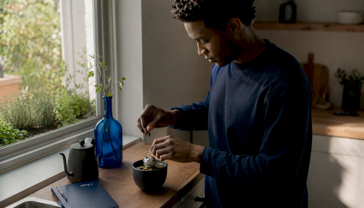 Man preparing green tea with infuser in kitchen