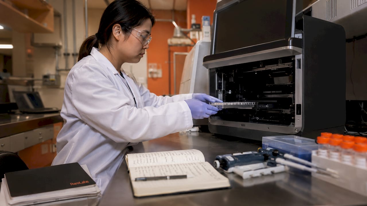 Technician loading genomic sequencer in lab