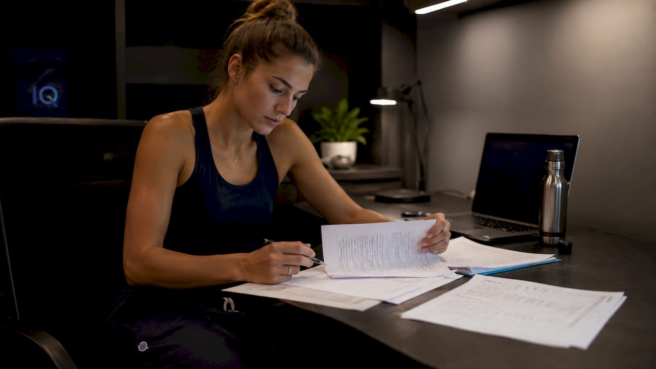 Athlete reviewing roster change documents at kitchen table