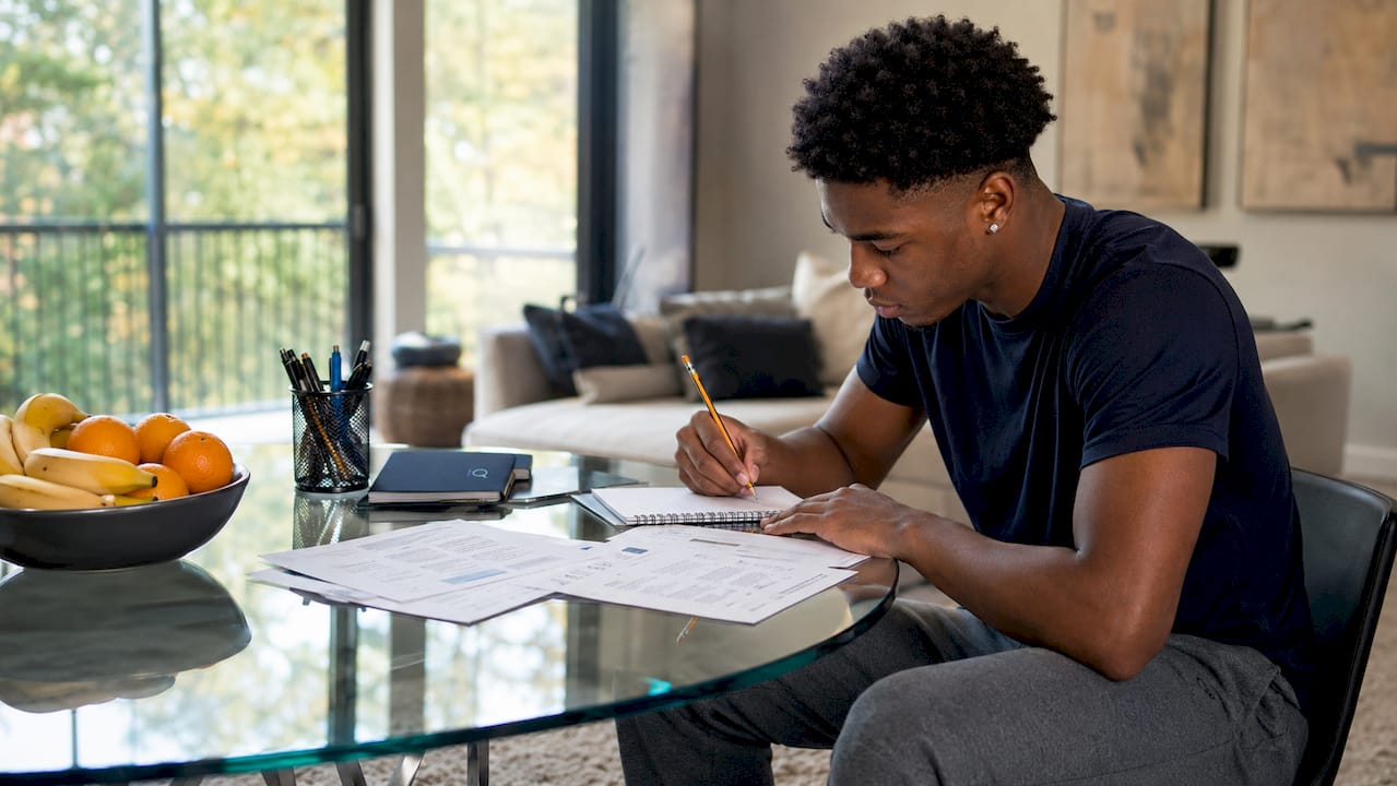 Basketball recruit reviewing scholarship papers at table
