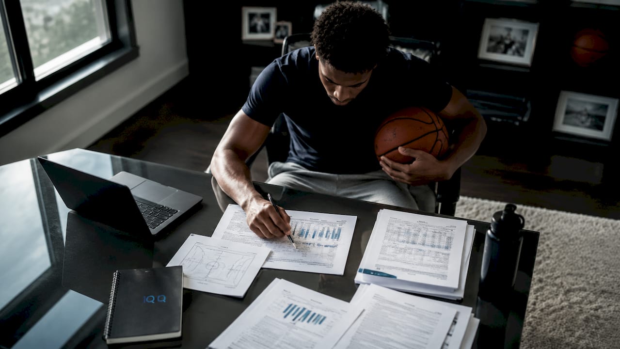 Basketball player reviewing transfer options at desk