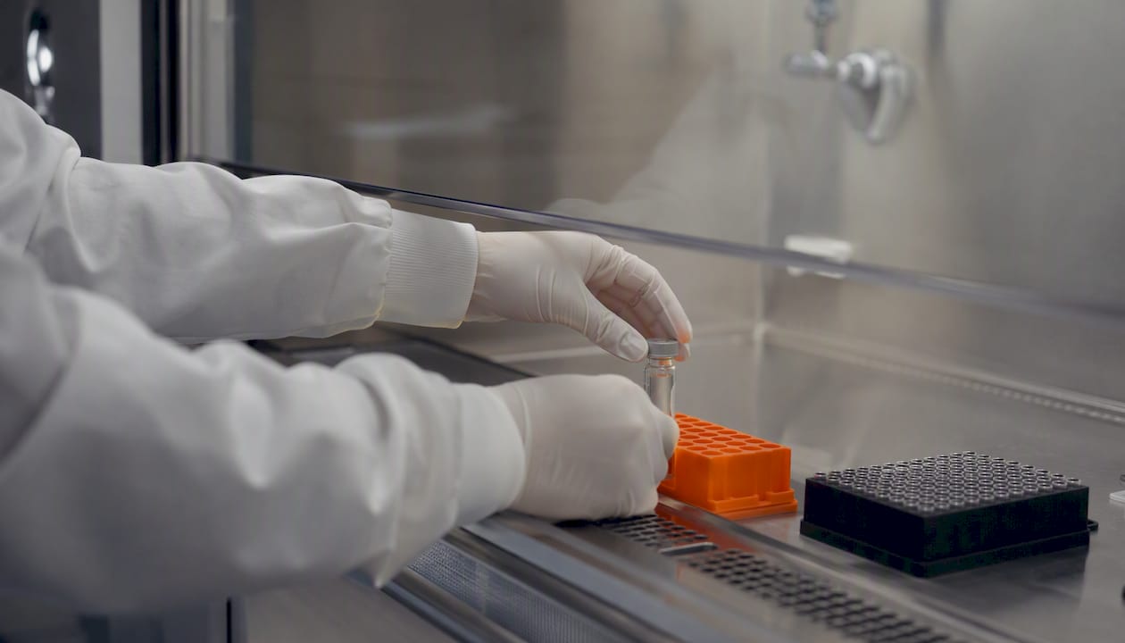 Une main place délicatement une cuvette dans le nucleofector.