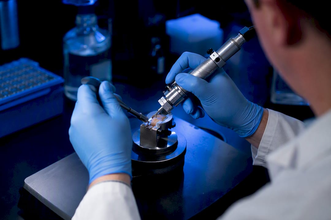 Hands preparing biopsy instrument in lab