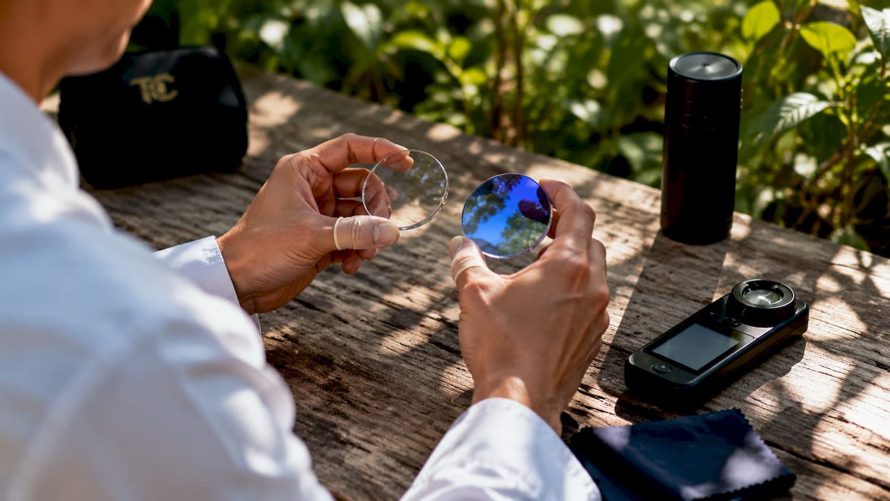 Close-up of hand inspecting UV coating on lenses