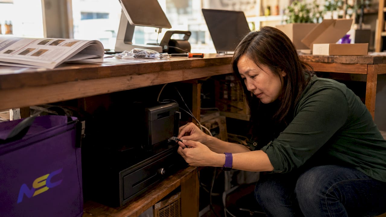 Woman installing POS hardware in retail shop