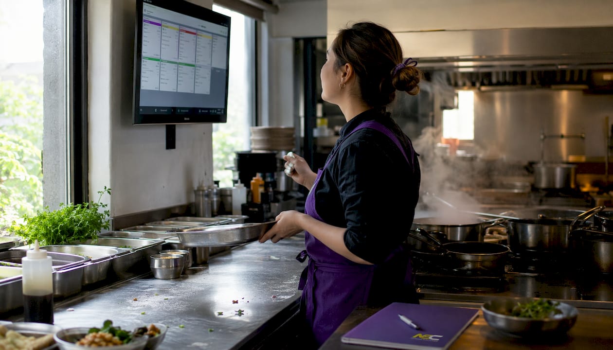 Chef checking digital kitchen order display screen