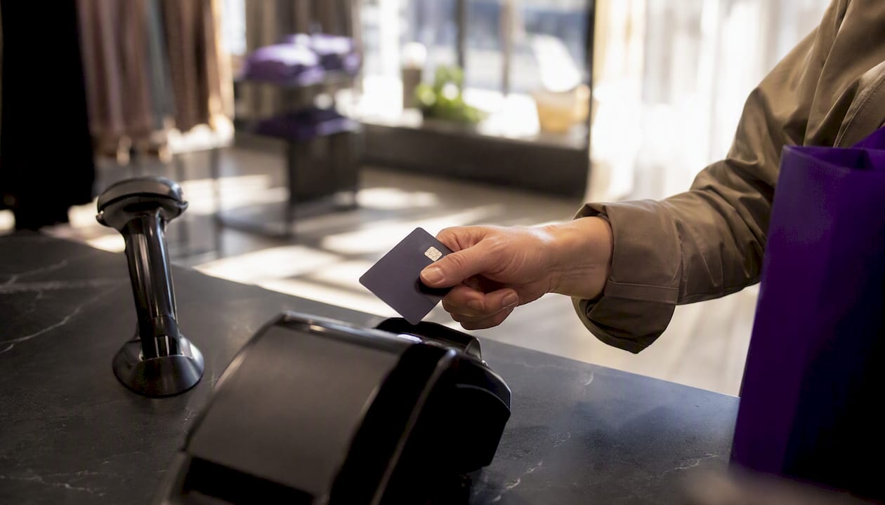 Hand holding card near payment terminal edge