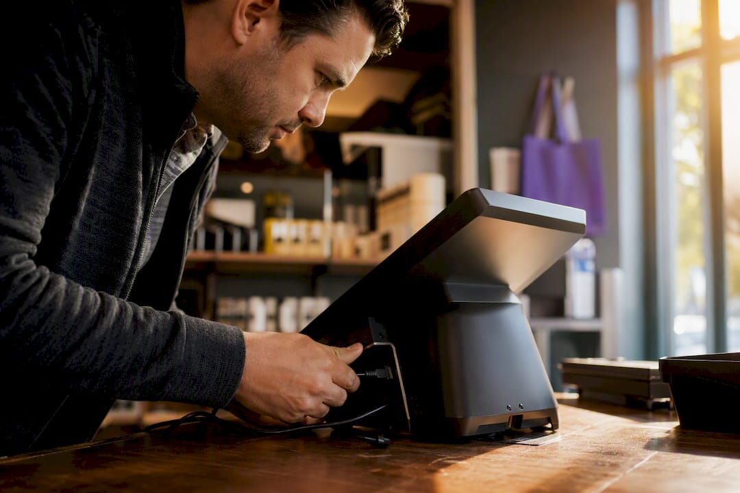 Hands connecting POS terminal cables for contactless setup