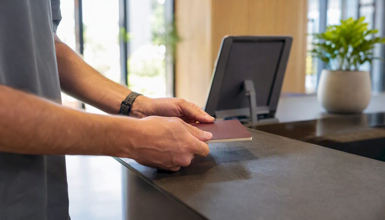 Una persona entrega su pasaporte sobre un mostrador elegante en una oficina moderna.