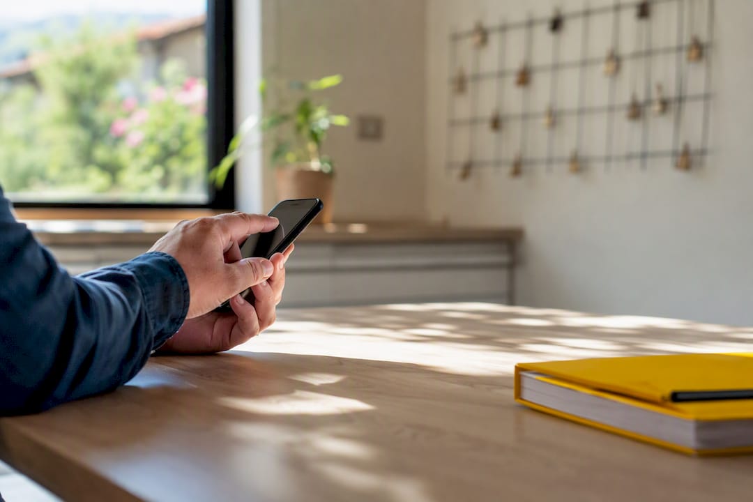 Mano che tocca lo smartphone vicino a un calendario sfocato
