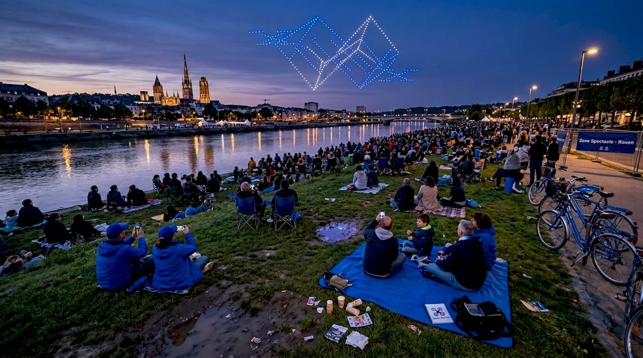 Un spectacle lumineux de drones en soirée, admiré par le public.