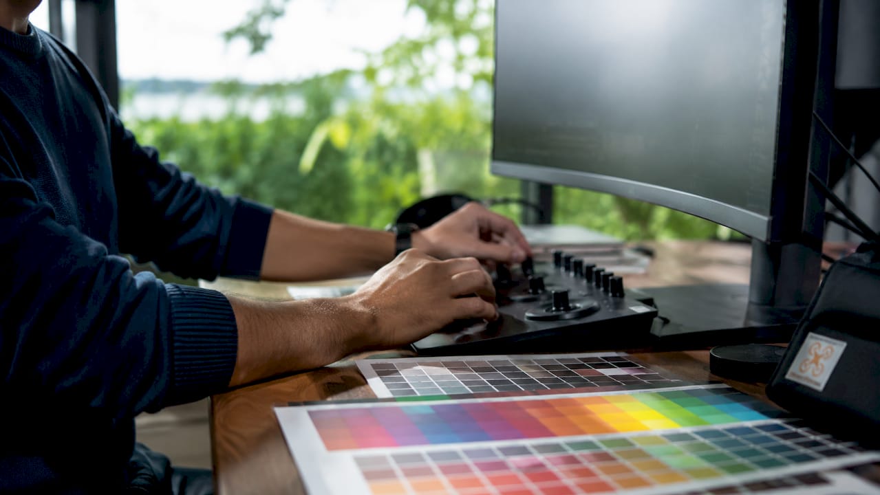 Des mains en train de régler les couleurs sur une console de post-production