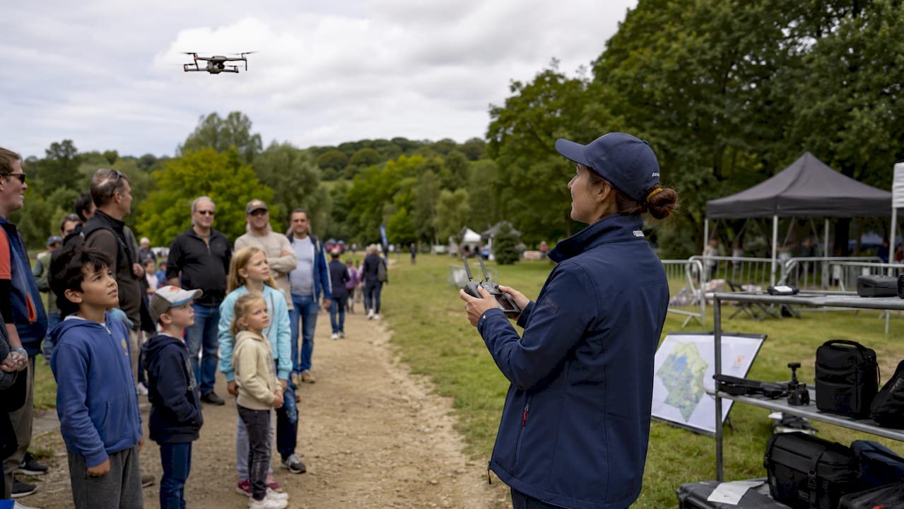Une femme pilote fait une démonstration de pilotage de drone en plein air.