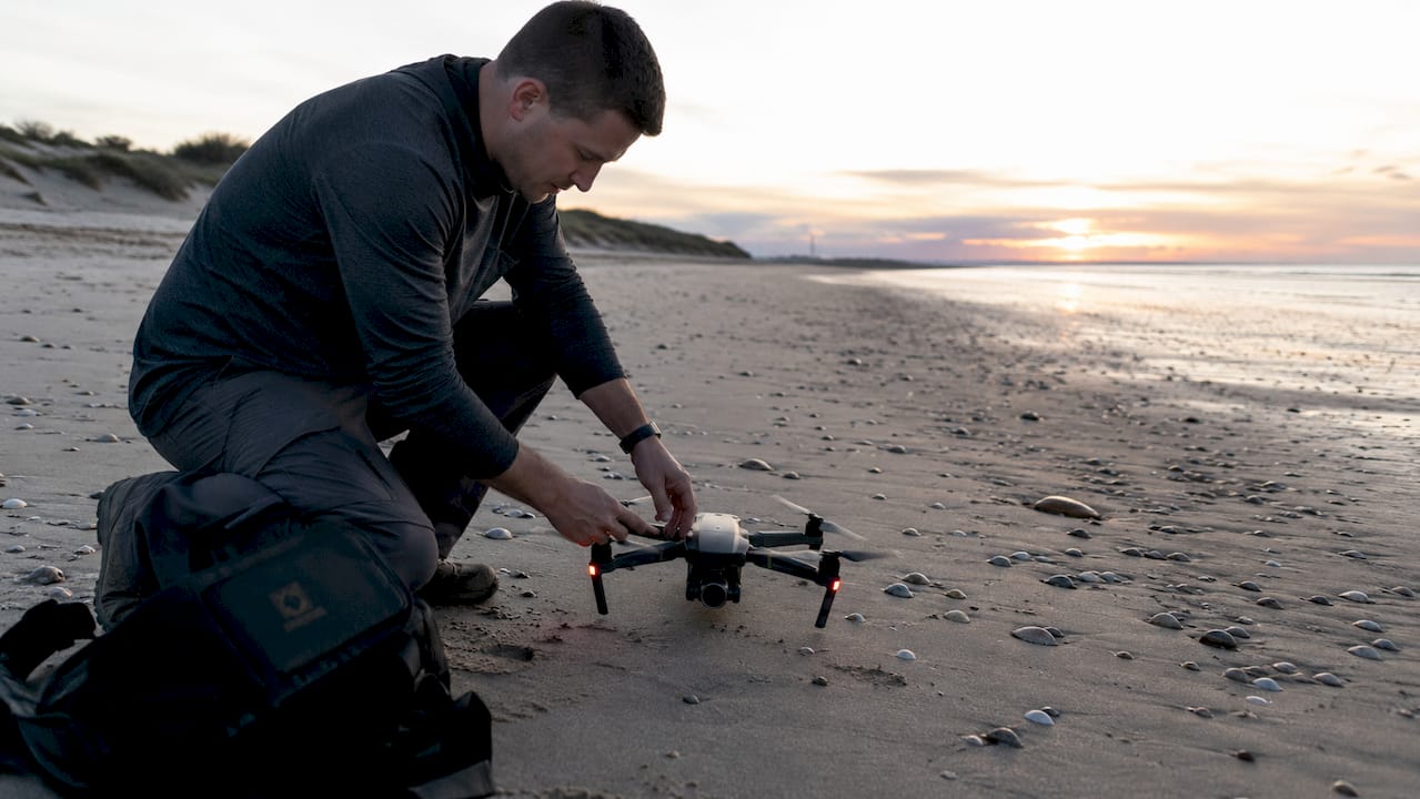 Un photographe installe son drone sur le toit d’un immeuble en ville.