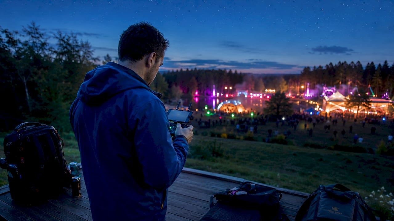 Un photographe pilote son drone au-dessus de la foule pendant une soirée de festival.