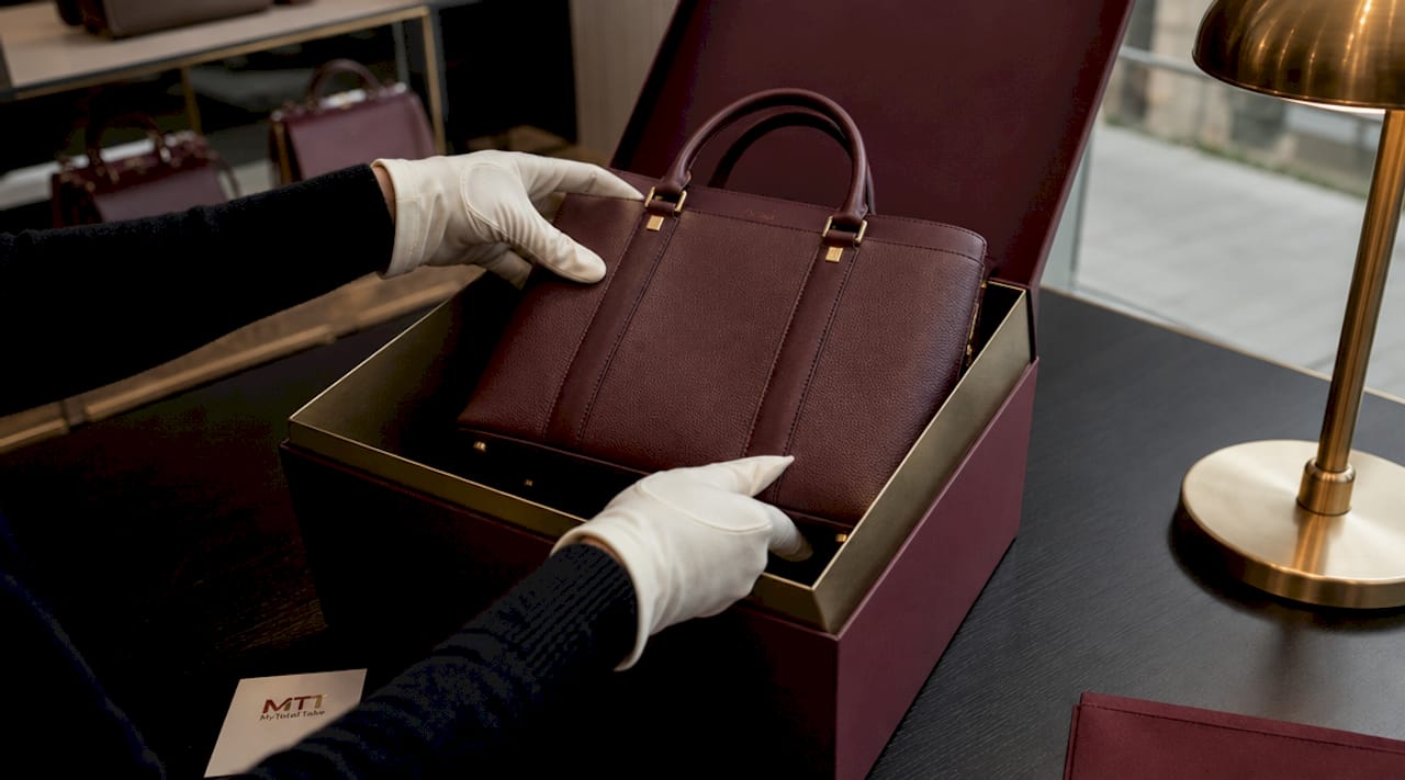 Hands packing luxury handbag with protective care