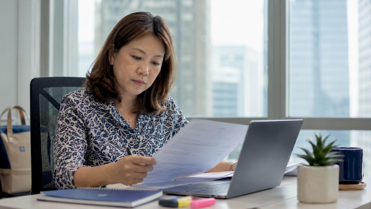Woman reviewing KITAS application documents at desk