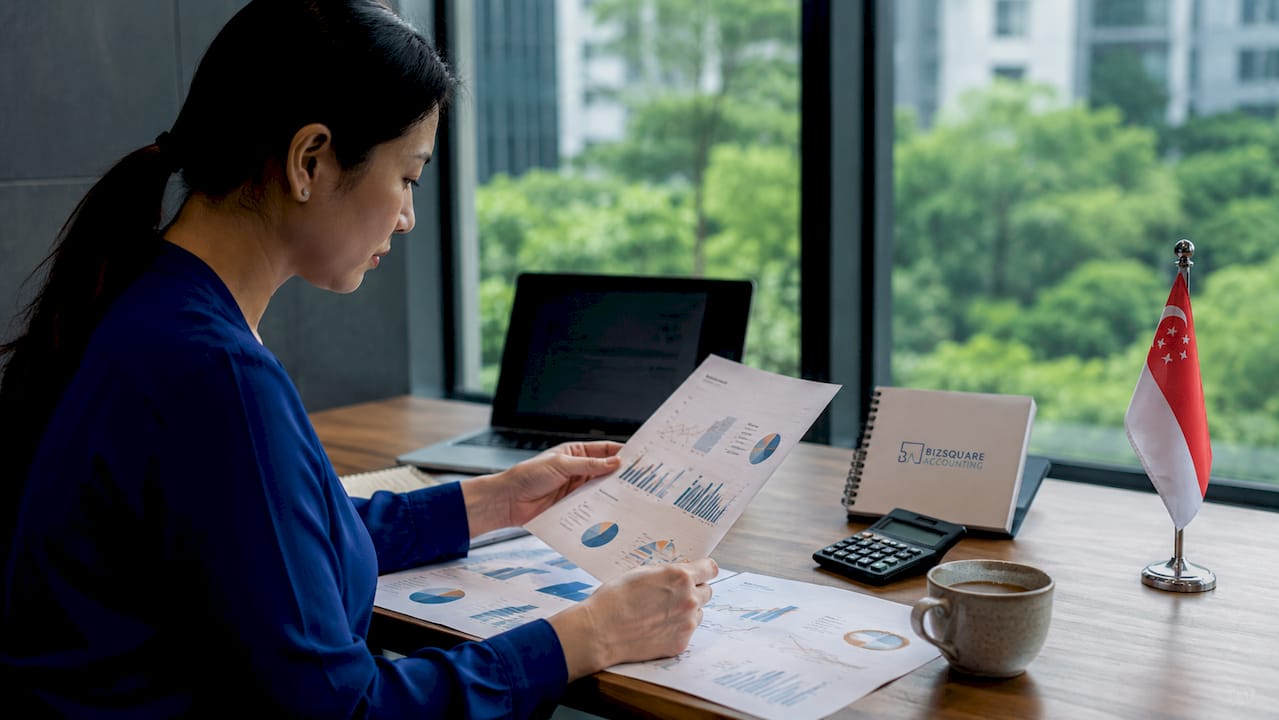 Hands reviewing Singapore tax documents on office desk