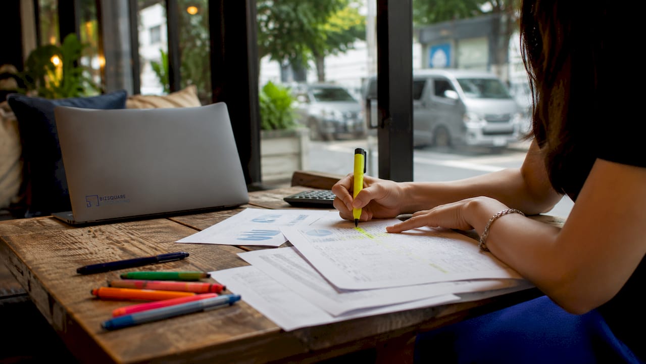 Hands marking business budget documents on desk