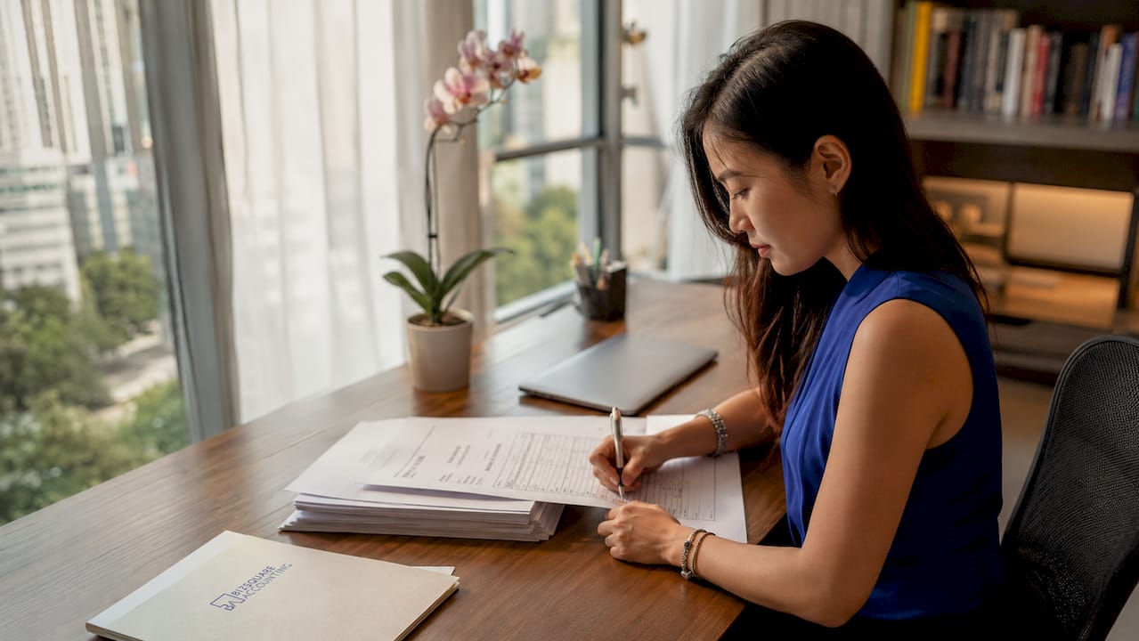 Hands signing company registration documents on desk in Singapore
