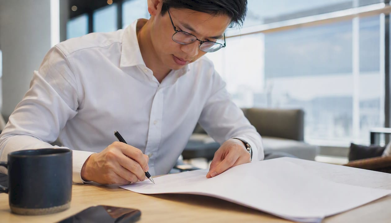 Hand signing share transfer document in Singapore office