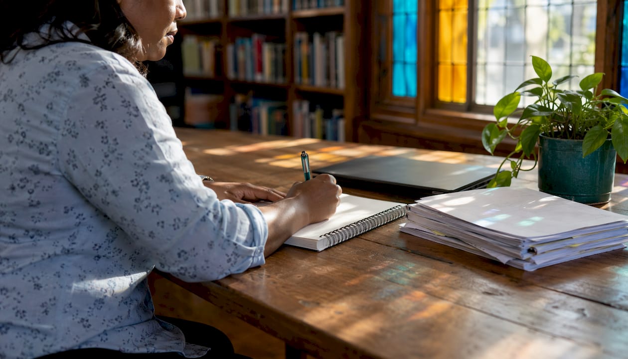 Teacher writing self-reflection notes in classroom