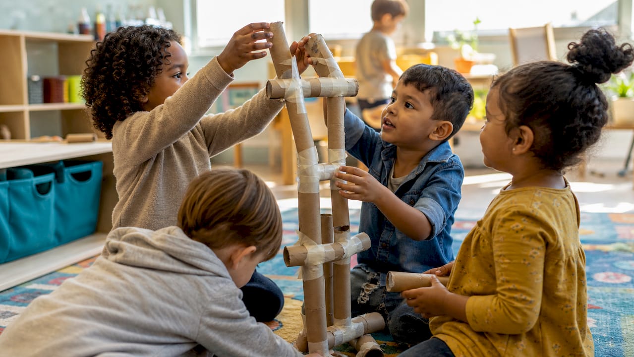Hands building a cardboard tube tower