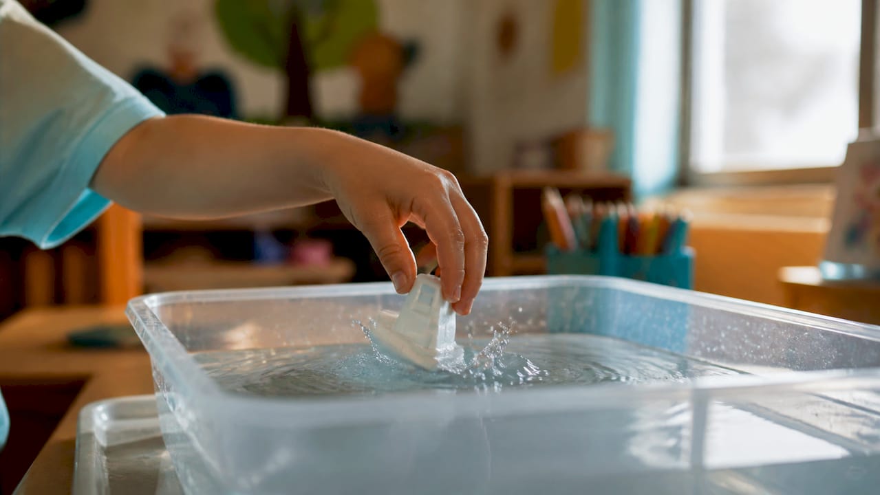 Child dropping object into water tub