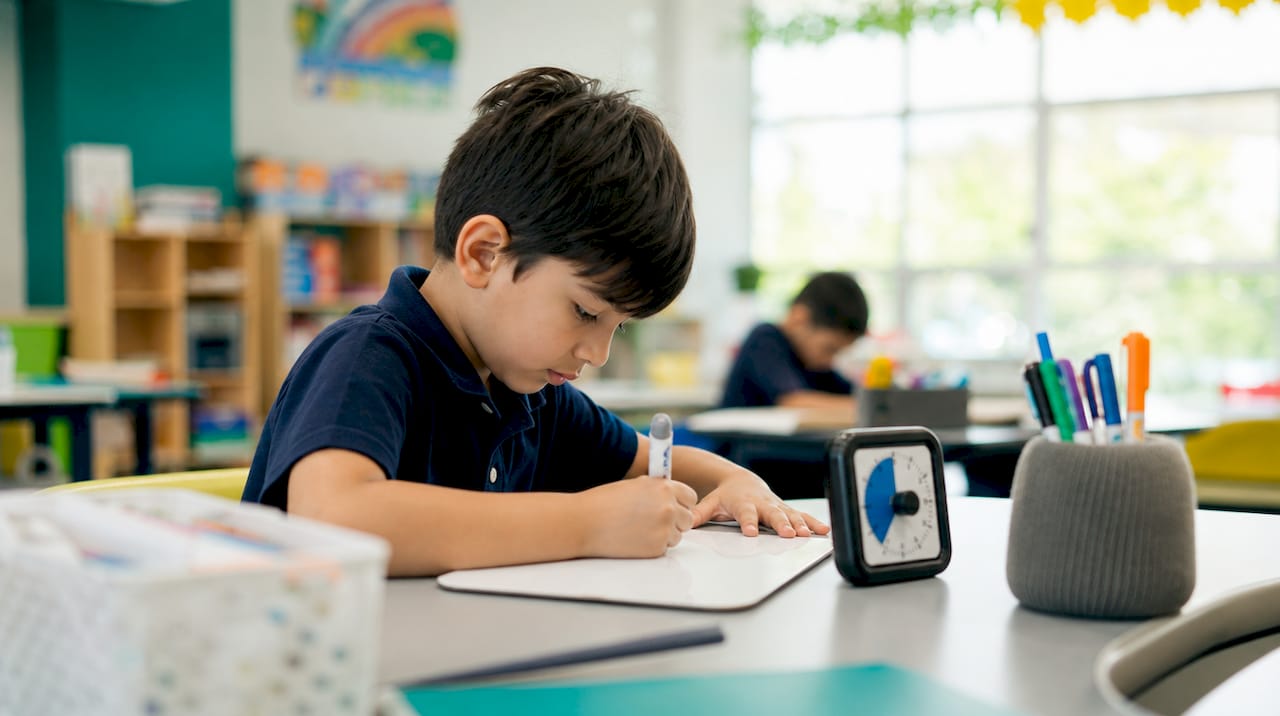 Child hands writing retrieval practice on mini whiteboard