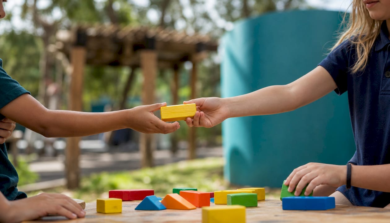 Children hands exchanging learning blocks cooperatively
