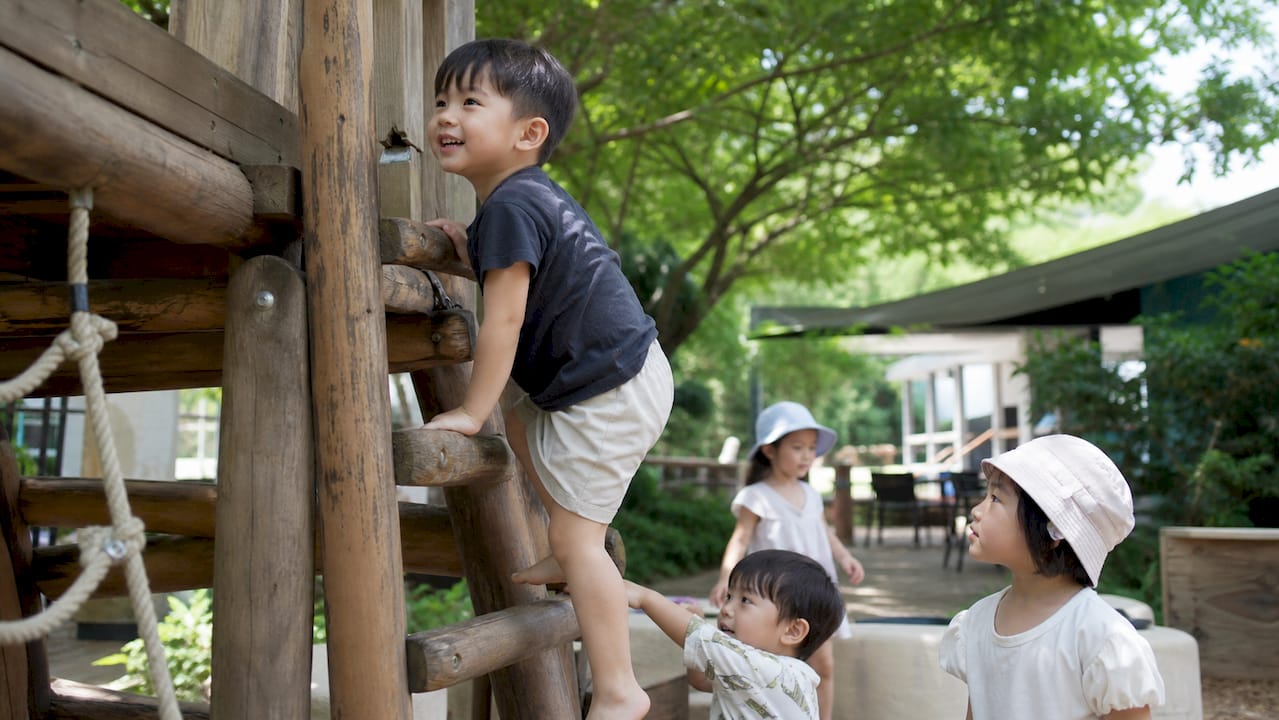 Child balancing on wooden beam at preschool playground