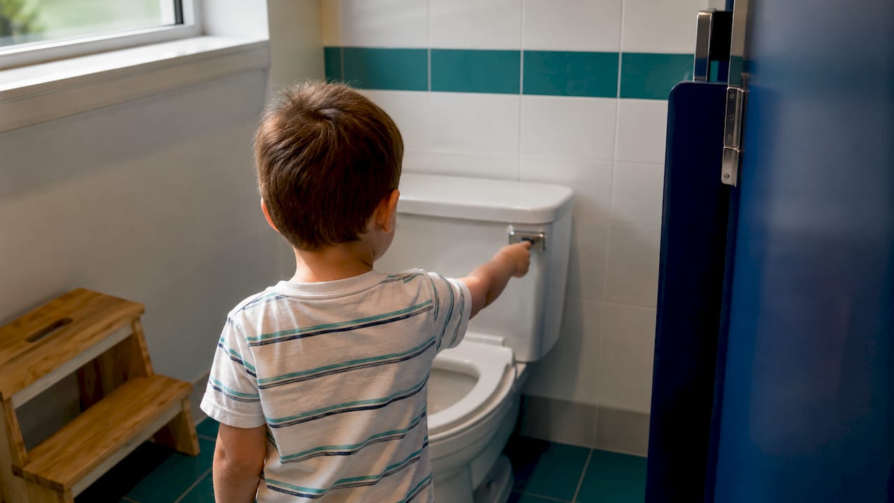 Child exploring unfamiliar preschool bathroom
