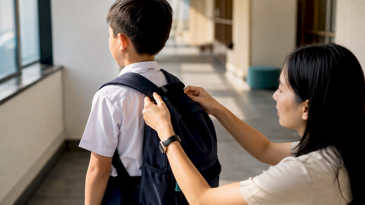 Parent adjusting child’s school bag straps