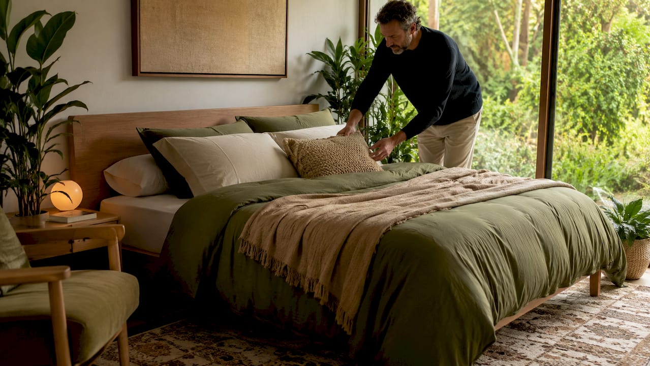 Man styling neutral plain dye bedding with textured accents