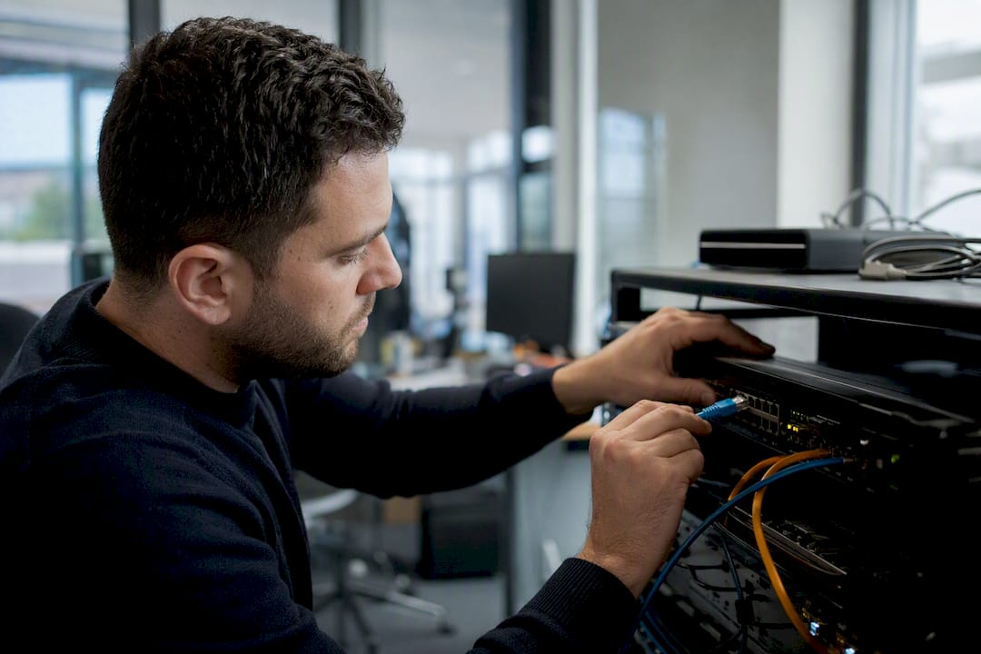 Hands plugging ethernet cable into switch