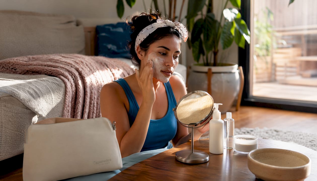 Young woman applying hydrating face mask at vanity