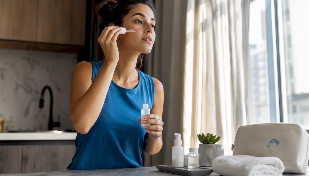 Woman applying antioxidant serum at vanity