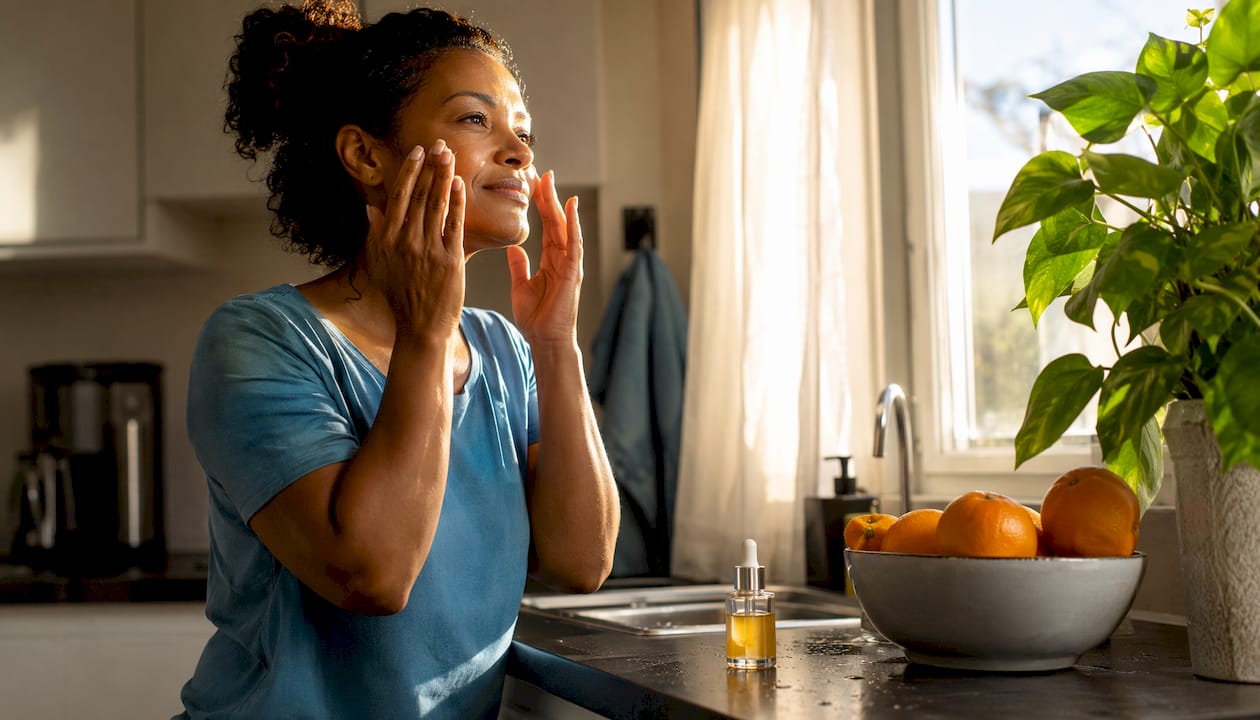 Woman applying vitamin C serum in bathroom