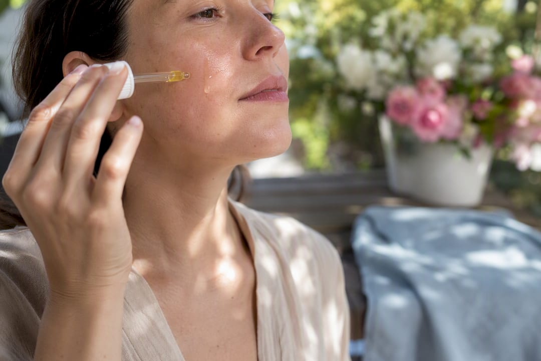 Close-up of hand applying facial oil to cheek