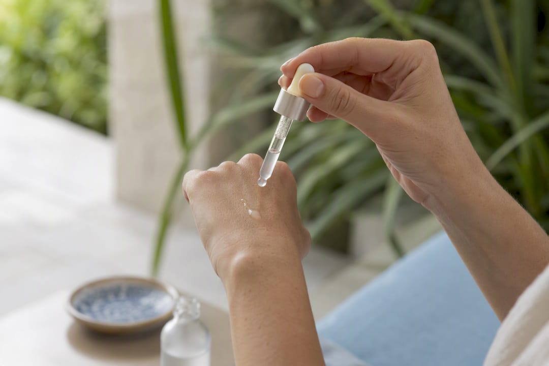 Hands applying serum dropper