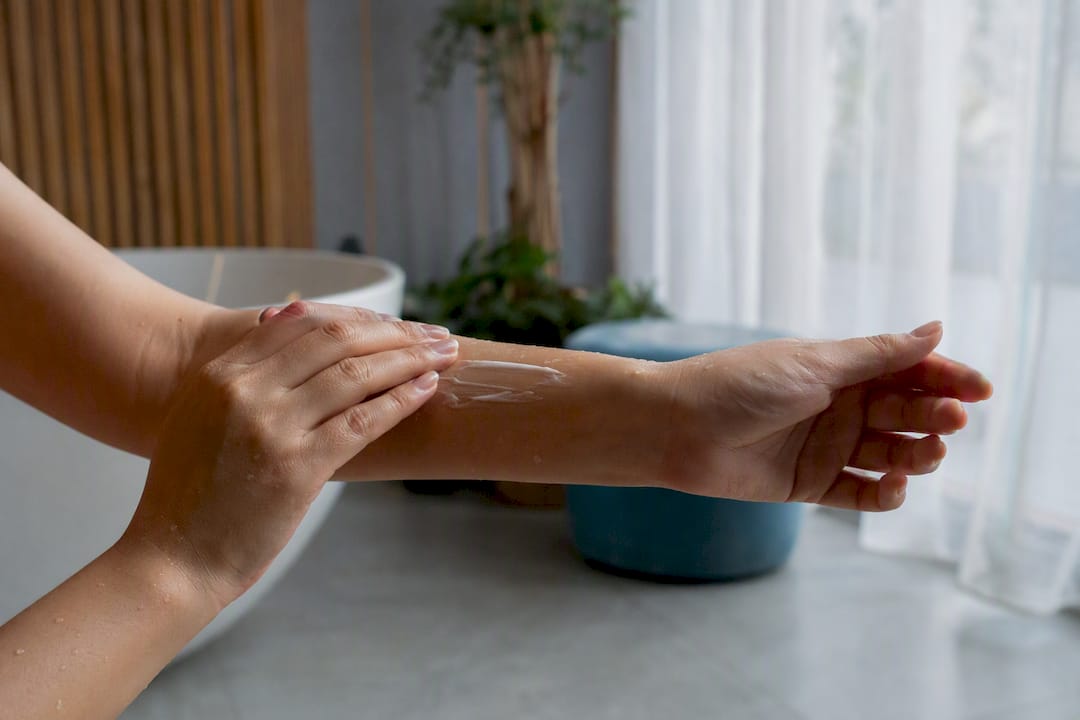 Hands layering serum and cream on damp skin
