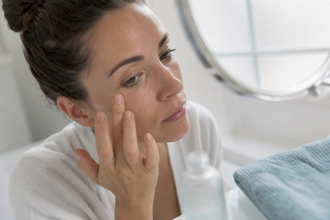 Woman gently applying retinol serum on dry skin