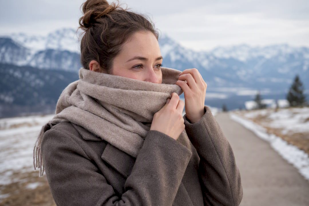 Woman protecting face with scarf outdoors